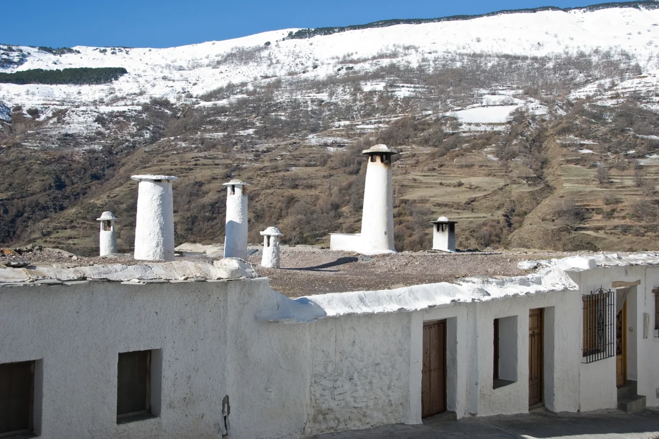 Imagen de unas casas de un típico pueblo de La Alpujarra de Granada con Sierra Nevada de fondo