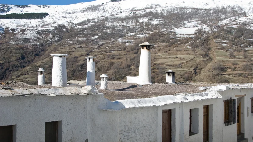 Imagen de unas casas de un típico pueblo de La Alpujarra de Granada con Sierra Nevada de fondo